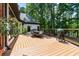 Spacious wooden deck with outdoor dining area, grill, and a view of a home and green trees at 6685 Driskell Rd, Cumming, GA 30041