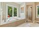 Bright bathroom with a soaking tub under a window overlooking a wooded area, and a glass enclosed shower at 6685 Driskell Rd, Cumming, GA 30041