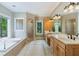 Bright bathroom featuring a large tub, dual sinks, wood cabinets, and a separate tiled shower at 6685 Driskell Rd, Cumming, GA 30041