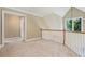 Carpeted bonus room featuring white railings, two doorways, and a window with green trees in the background at 6685 Driskell Rd, Cumming, GA 30041