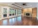 Open-concept living room with hardwood floors, fireplace, built-in shelving and large windows to outside view at 6685 Driskell Rd, Cumming, GA 30041