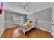 Bright bedroom featuring hardwood floors, a ceiling fan, and a large window at 964 Natural Brook Trl, Lawrenceville, GA 30045