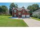 Inviting brick home featuring a two-car garage, manicured lawn, and a charming front entrance with decorative windows at 503 Rising Dr, Woodstock, GA 30189