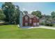 Charming exterior view of a brick home with a lush green lawn, mature trees, and a two-car garage at 503 Rising Dr, Woodstock, GA 30189