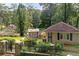 Backyard view of the house and guest house, surrounded by greenery and with a stone retaining wall at 1530 Niskey Lake Sw Trl, Atlanta, GA 30331