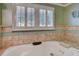 A relaxing soaking tub is situated beneath a window with classic plantation shutters at 1530 Niskey Lake Sw Trl, Atlanta, GA 30331