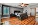 Comfortable main bedroom with hardwood floors, a ceiling fan, and a large bed with built-in storage, exuding warmth at 1530 Niskey Lake Sw Trl, Atlanta, GA 30331