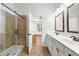 Bright bathroom featuring double vanity, framed mirrors, and a tiled shower with sliding glass door at 3541 Ashcroft Se Dr, Smyrna, GA 30080