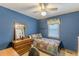 Blue bedroom showcasing a bed with colorful quilt, wooden dresser and ceiling fan at 4411 Westerling Ct, Powder Springs, GA 30127