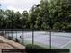Outdoor tennis court with black chain link fence, lush surrounding greenery and park benches at 22 Dunwoody Springs Dr, Atlanta, GA 30328