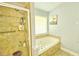 Bathroom includes a tiled shower with seating and soaking tub under window at 2233 Hansford Pass, Buford, GA 30519