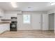 Well-lit kitchen featuring white cabinets, black appliances, and wood-look floors at 502 Snowfall Ter, Palmetto, GA 30268