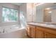 Well-lit bathroom featuring double sinks, vanity, and large tub under a window at 5033 Kens Ct, Stockbridge, GA 30281