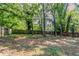 View of the home's backyard with partial lawn, mature trees, and fenced perimeter at 5383 Forest East Ln, Stone Mountain, GA 30088