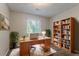 Bright office featuring a wooden desk, a wall of shelving, a laptop, and natural light from a large window at 5383 Forest East Ln, Stone Mountain, GA 30088