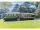 Charming brick home with a manicured front lawn and a red front door at 573 Allgood Rd, Stone Mountain, GA 30083