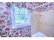 Vintage-style bathroom with neutral tiled walls and a floral wallpaper accent at 4581 Newcastle Cir, Lithonia, GA 30038