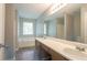 Bathroom featuring double sinks, large mirror, soaking tub, and stylish wood-look flooring at 5867 Heritage Walk, Lithonia, GA 30058