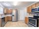 Well-equipped kitchen featuring stainless steel appliances, wooden cabinets, tile flooring, and ample counter space at 5867 Heritage Walk, Lithonia, GA 30058