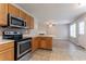 Bright kitchen with stainless steel appliances, wooden cabinetry, a breakfast bar, and views into the living room at 5867 Heritage Walk, Lithonia, GA 30058