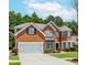 Traditional two-story red brick home with a manicured lawn, attached two car garage and a circular driveway at 2023 Jameson Cir, Lawrenceville, GA 30043