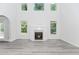 Living room area with a fireplace, gray wood floors, three windows, and glass doors to the backyard at 2023 Jameson Cir, Lawrenceville, GA 30043