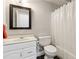 Compact bathroom with white vanity, black floor tile, toilet, and a shower/tub with curtain at 2713 Misty Rock Cv, Dacula, GA 30019