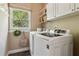 Laundry room with white washer and dryer, cabinets, and a window overlooking green trees at 2713 Misty Rock Cv, Dacula, GA 30019