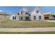 Charming two-story home boasts white brick and siding, complemented by blue shutters and a well-manicured lawn at 443 Lothbury Ave, Locust Grove, GA 30248