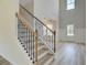 Stylish staircase with iron balusters, wood handrail, and plenty of natural light from the nearby door at 443 Lothbury Ave, Locust Grove, GA 30248