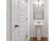 Compact powder room with pedestal sink, modern fixtures, and sleek, white door at 6761 Cedar Glen Rd, Peachtree Corners, GA 30360