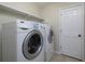 Laundry room with a white washer and dryer, and white shelving above. Features tile flooring at 21 Queen Anne Se Dr, Mableton, GA 30126