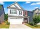 Inviting two-story home with an attached garage, well-manicured lawn, and charming curb appeal on a sunny day at 2859 Woodward Down Trl, Buford, GA 30519
