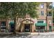 Street view showcasing a mixed use building with shops and balconies covered by a lush tree at 230 E Ponce De Leon Ave # 104, Decatur, GA 30030