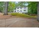 View of home exterior featuring lush lawn and a long driveway, with mature trees in the background at 9805 Buice Rd, Alpharetta, GA 30022