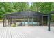 Screened in pool enclosure with pool furniture and a scenic view of the wooded backyard at 9805 Buice Rd, Alpharetta, GA 30022