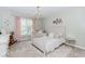 This light and airy bedroom is decorated with a crystal chandelier, pink curtains, and neutral furniture at 2115 Bentbrooke Trl, Lawrenceville, GA 30043
