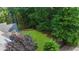 An aerial view of the backyard highlighting a large, grassy area surrounded by mature trees at 3737 Falls Trl, Winston, GA 30187