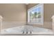 Clean bathroom featuring a large soaking tub, tiled floor, and a window view at 3737 Falls Trl, Winston, GA 30187