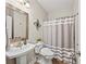 Bathroom featuring a pedestal sink, toilet, and shower with gray and white striped curtain at 7198 Golfside Se Dr, Covington, GA 30014