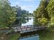 Picturesque pond with a wooden bridge amidst lush trees, offering a tranquil view at 7198 Golfside Se Dr, Covington, GA 30014
