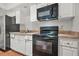 Close up of a kitchen featuring white cabinets and black appliances at 2241 Chaseford Ln, Powder Springs, GA 30127