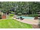 Expansive backyard featuring a pool, well-maintained lawn, lounge chairs, and a surrounding wooded area at 140 Silvermere, Fayetteville, GA 30215