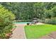 Landscaped backyard showcasing a pool, patio furniture, and manicured lawn surrounded by trees at 140 Silvermere, Fayetteville, GA 30215