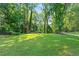 Manicured backyard with lush trees, green grass, and an open space at 2461 Fernleaf Nw Ct, Atlanta, GA 30318