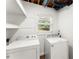 Functional laundry area with a washer, dryer, shelves, window, and exposed ceiling beams at 6875 Sunny Brook Lane Northeast, Sandy Springs, GA 30328