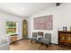 Bright living room with wood floors, large print art, and unique decorations, with a window view to a back deck at 6875 Sunny Brook Lane Northeast, Sandy Springs, GA 30328