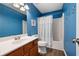 Cozy bathroom featuring a vanity, toilet, and shower-tub combo, all complemented by vibrant blue walls at 245 Weatherstone Pointe Dr, Woodstock, GA 30188