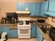 Kitchen features include outdated blue cabinets, tan granite countertops, and a white gas range at 8564 Jamestown Way, Jonesboro, GA 30238
