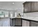 Modern kitchen with stainless steel appliances, dark gray cabinets, quartz countertops, and gray wood flooring at 969 Bob Hannah Cir, Lawrenceville, GA 30044
